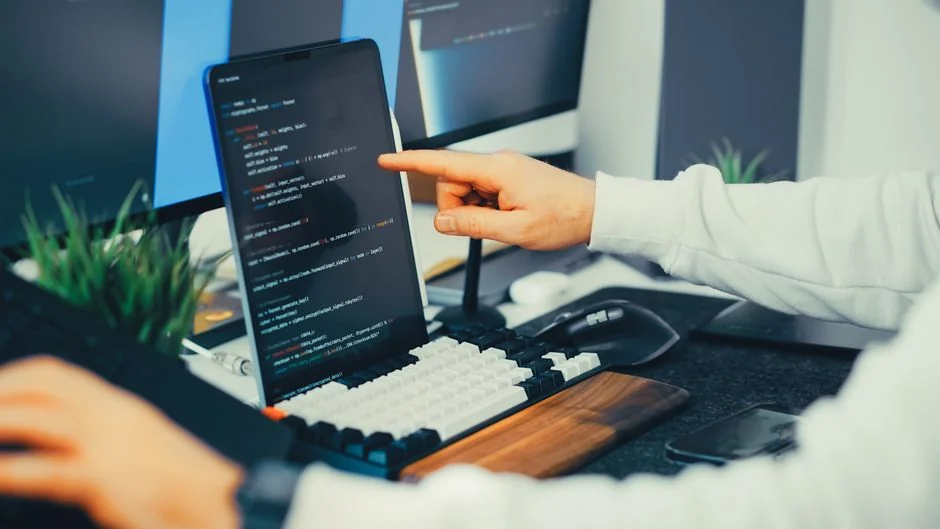 Rear view of a cropped anonymous male freelancer seated at a table, working on a project on a laptop in a bright room during the day